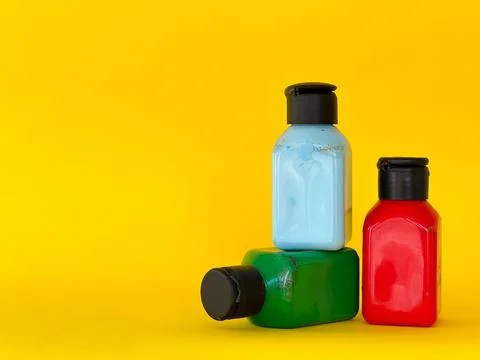 Jars with bright multi-colored acrylic paint on a yellow background. Still life Foto stock