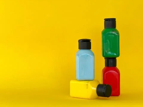 Jars with bright multi-colored acrylic paint on a yellow background. Still life Stock Photos