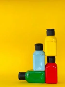 Jars with bright multi-colored acrylic paint on a yellow background. Still life Stock Photos