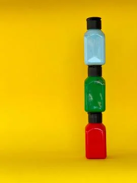 Jars with bright multi-colored acrylic paint on a yellow background. Still life Stock Photos