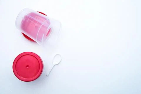 Jars for collecting tests with a red lid and a spoon on a white background. Stock Photos