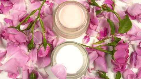 Jars with face cream, fresh pink roses are on a white table, top view Stock Footage 337404014