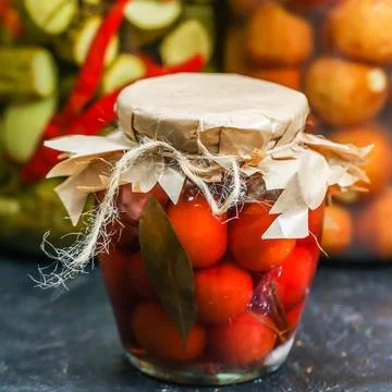 Jars filled with cherry tomatoes and spices in a kitchen setting 库存照片