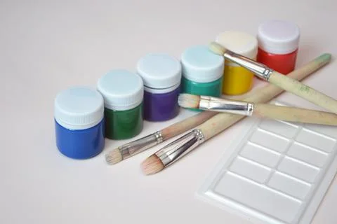 Jars with multi-colored gouache paints and a set of artistic brushes. Artist' Stock Photos