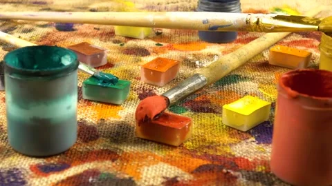 Jars with paints, paint brushes lay out on a beige burlap fabric  Stock Footage 333569233