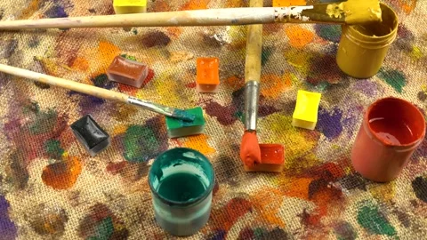 Jars with paints, paint brushes lay out on a beige burlap fabric  Stock Footage 333569239