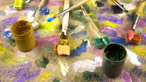 Jars with paints, paint brushes lay out on abstract background  Stock Footage 333569747