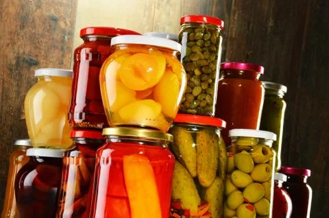 Jars with pickled vegetables, fruity compotes and jams Stock Photos