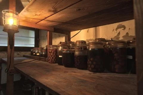 Jars with pickled vegetables, fruity compotes and jams in abandoned basement Stock Photos