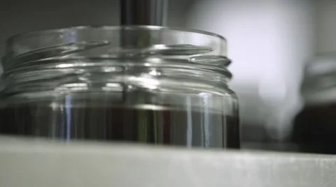 Jars on a production line being filled with syrup Stock Footage 60443112