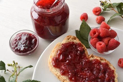 Jars of raspberry jam and a white plate with toast Stock Photos