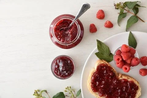 Jars of raspberry jam and a white plate with toast Stock Photos