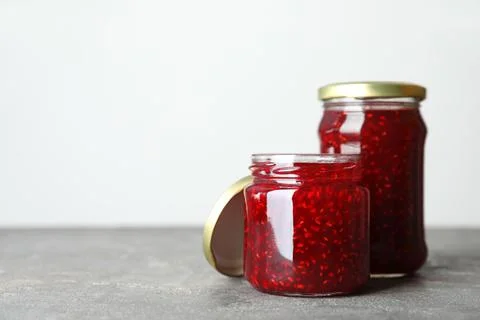 Jars of raspberry jam on grey table. Space for text Stock Photos