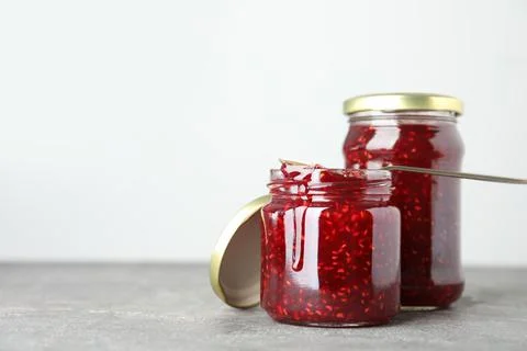 Jars of raspberry jam on grey table. Space for text Stock Photos