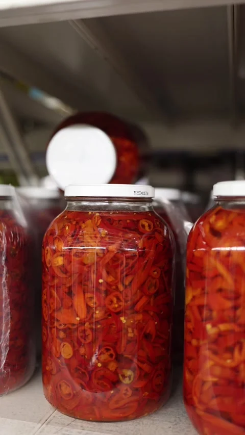 Jars of sliced red chili peppers preserved in brine on store shelves Stock Footage 345977823