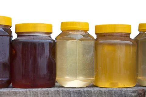 Jars with yellow plastic lids with different types of honey Stock Photos