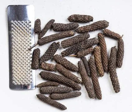 Java long pepper with grater close up on gray top view of java long pepper... Stock Photos