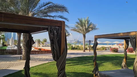 JBR Beach, Dubai UAE, Cabanas in Garden, Parasols and Ferris Wheel in 動画素材 202537206