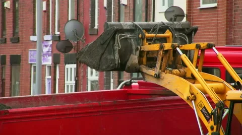 JCB 2CX backhoe loader loading spoil from road resurfacing work into a lorry Stock Footage 61724563