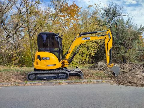 JCB digger or excavator performs excavation work outdoors Stock Photos