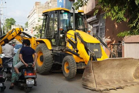 JCB earth moving machine working on a road. JCB bucket loader is repairing a  Stock Photos