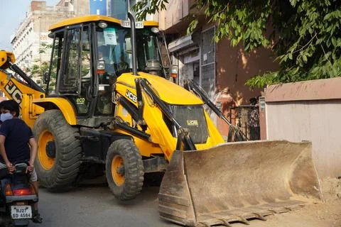 JCB earth moving machine working on a road. JCB bucket loader is repairing a Stock Photos