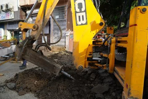 JCB earth moving machine working on a road. JCB bucket loader is repairing a  Stock Photos