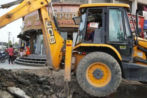 JCB earth moving machine working on a road. JCB bucket loader is repairing a  Stock Photos