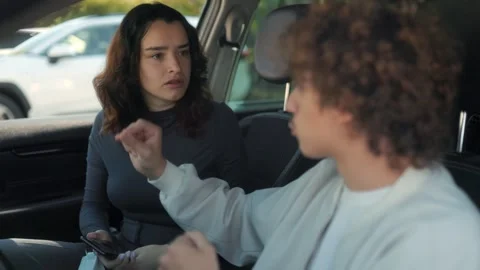 Jealous girlfriend shouting at boyfriend while holding smartphone in car Stock Footage 316456188