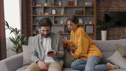 Jealous young woman trying to have a peek into the boyfriend smartphone. Cheater Stock Footage