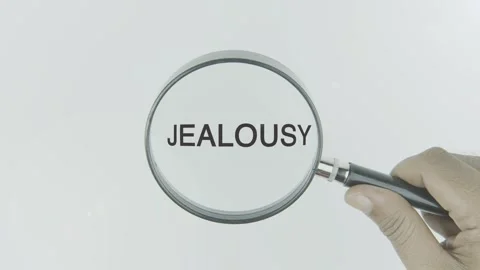 Jealousy text or word highlighted by a magnifying glass in a hand on a white Stock Footage 303659004