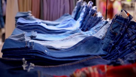 Jeans of different models and colors are on the counter in the supermarket Stock Footage 149208574