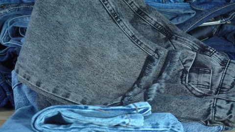 Jeans fall in slow motion onto a pile of denim pants. Stock Footage 233729911