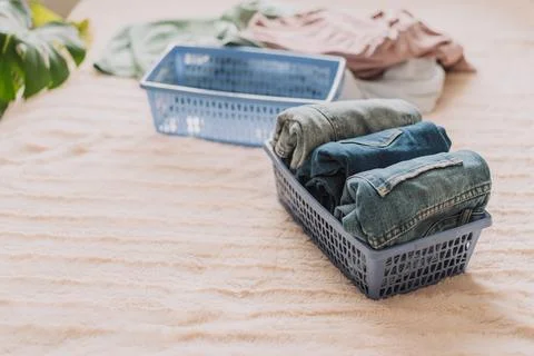 Jeans folded into blue container on the bed Stock Photos