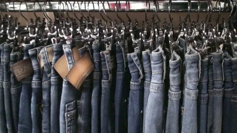 Jeans hanging on hangers on the rack Stock Footage 76709552