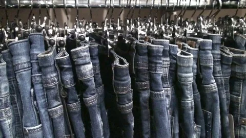 Jeans hanging on hangers on the rack in the store Stock Footage