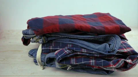 Jeans, pajama, shirts falling on the table in a stack. Clothes for donation Stock Footage 135582942