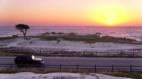 Jeep Driving Past Pebble Beach at Sunset by Aerial Drone Stock Footage