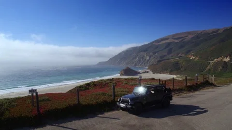Jeep parking off PCH in Big Sur by Aerial Drone Stock Footage 80963859