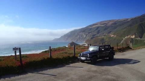 Jeep parking off PCH in Big Sur by Aerial Drone Stock Footage 80963876