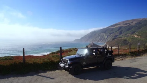 Jeep parking off PCH in Big Sur by Aerial Drone Stock Footage 80963881