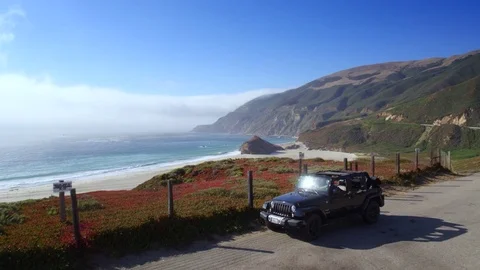 Jeep parking off PCH in Big Sur by Aerial Drone Stock Footage 80963889