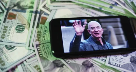 Jeff Bezos Image on iphone surrounded by $100 Bills. Besos Rich Layout Stock Footage 169006896