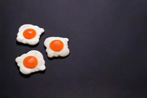 Jelly fried eggs on the left on a black background close-up Stock Photos