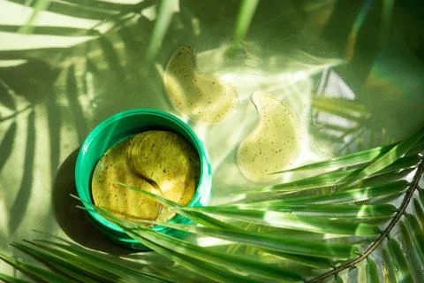 Jer hydro gel eye patch on green background with palm leaves and water highli Stock Photos