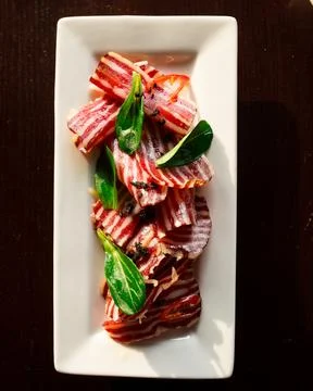 Jerky striped venison platter with basil leaves Stock Photos