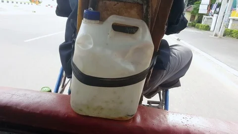 Jerrycan full with petrol strapped to back seat of tuk-tuk driver while driving Vidéo 74988216