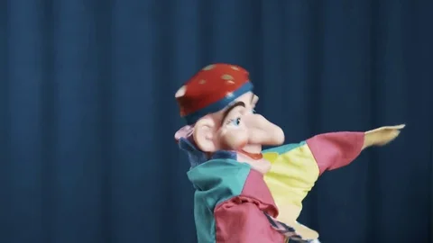 Jester hand puppet dancing and spread arms on scene with blue background Video stock 73025662