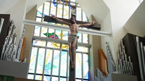 Jesus hangs on the cross, illuminated backlight by the window in church Stock Footage 279792023