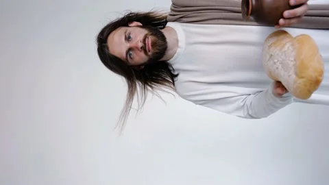 Jesus is holding a jug and bread on a white background. Studio. Close up. Video stock 160494635